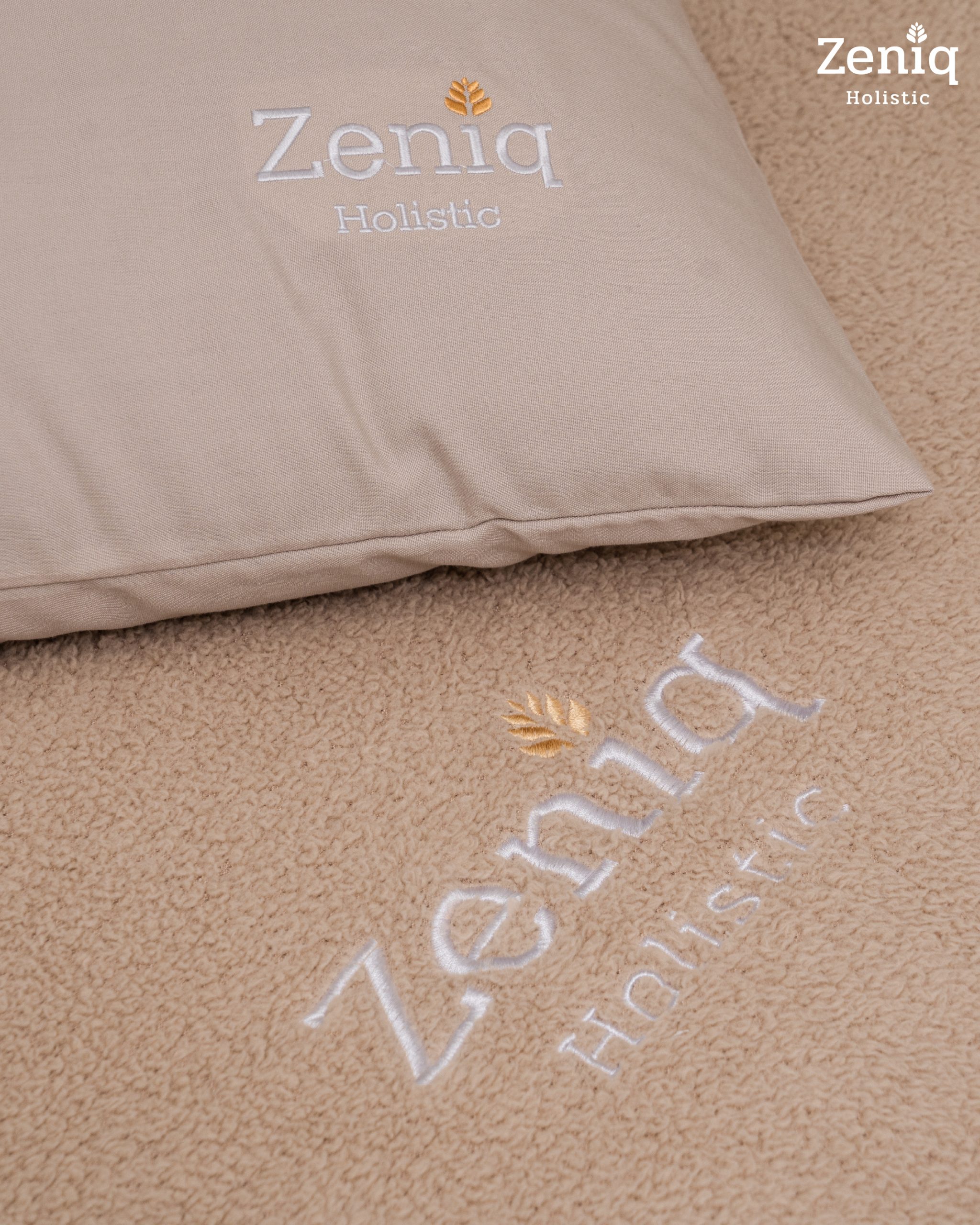 Close-up of premium treatment bed linens embroidered with the Zeniq Holistic logo.